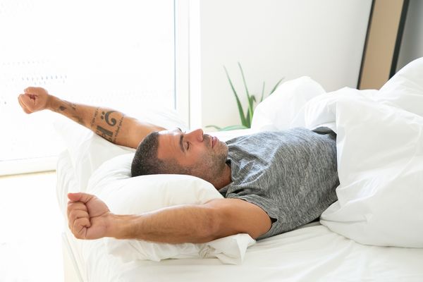 man waking up in morning in bed